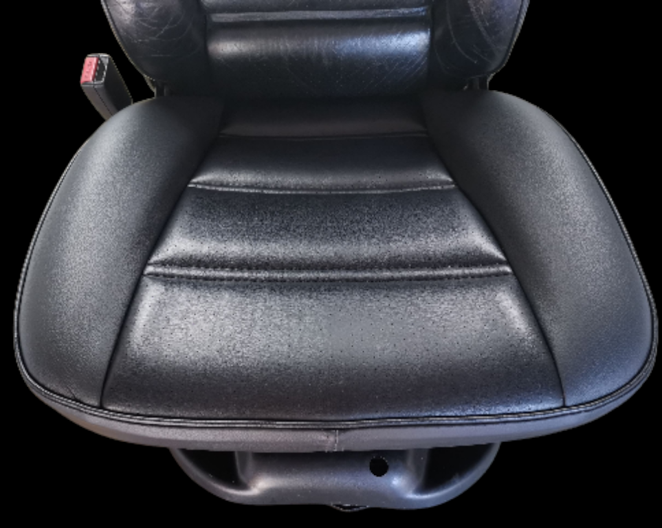 Black leather car seat with horizontal stitching and seatbelt.