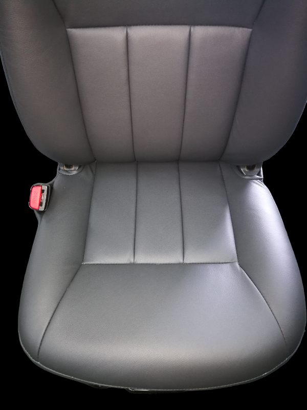 Black leather car seat with three vertical stitched sections and a red seatbelt buckle.