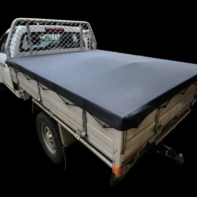 Gray tarp covering a pickup truck bed, against a black backdrop.