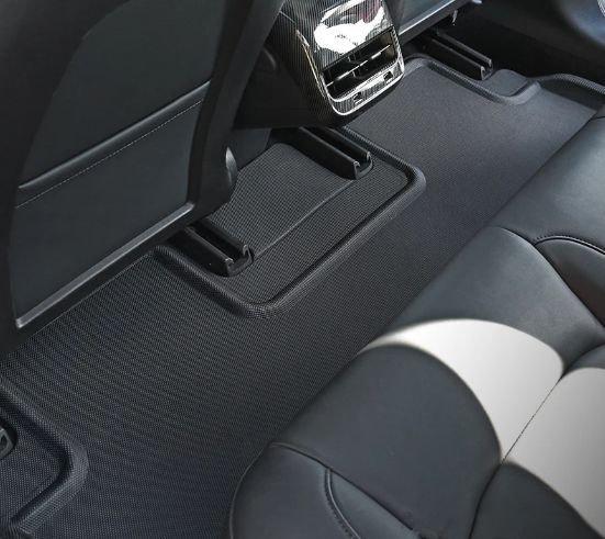 Black rubber floor mats in the backseat of a car. The mats cover the floor.