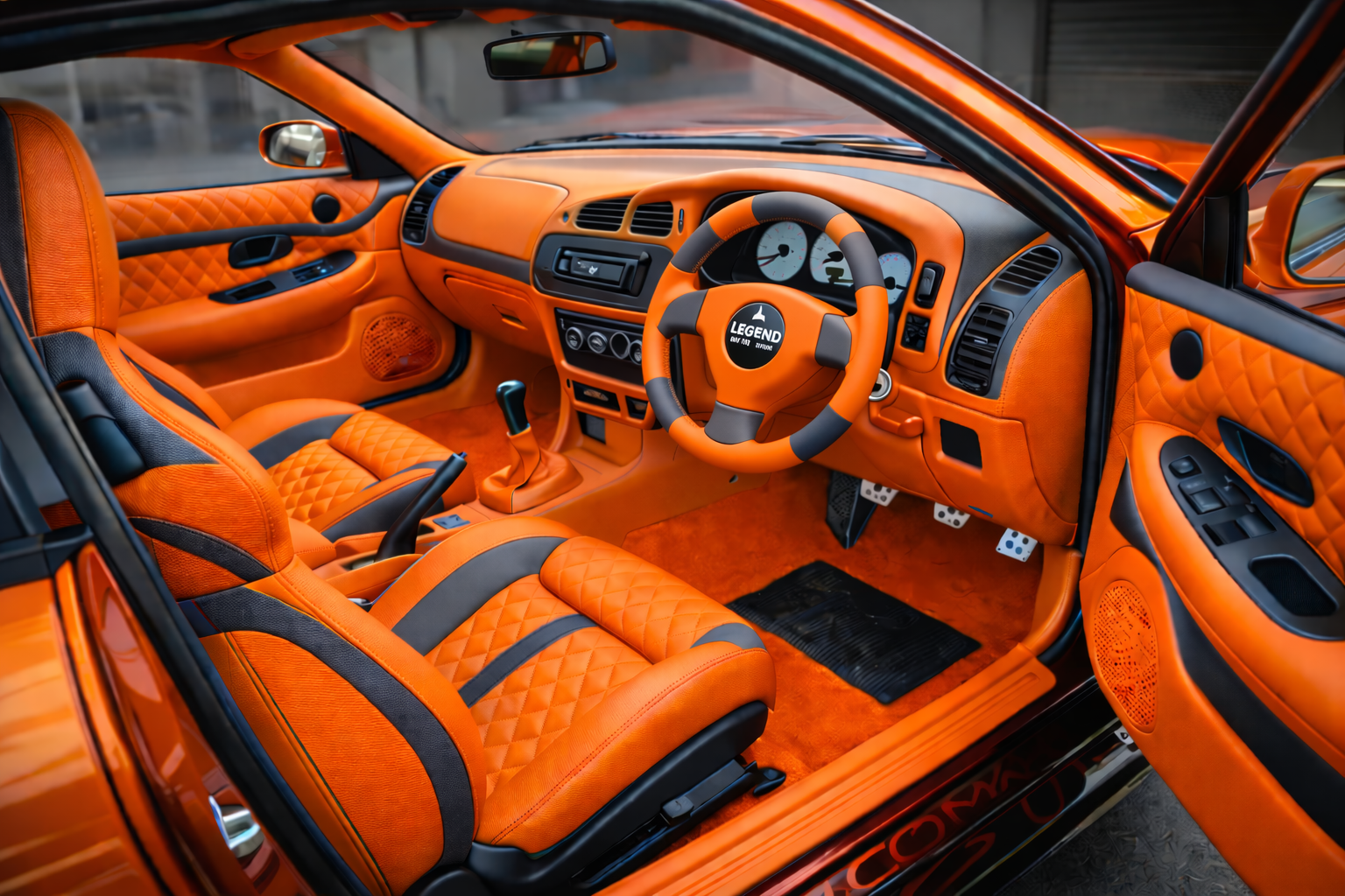 Bright orange car interior with quilted leather seats, gray accents, and black floor mats.