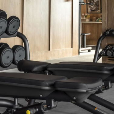 Weight bench and dumbbell rack in a gym with wood paneling.