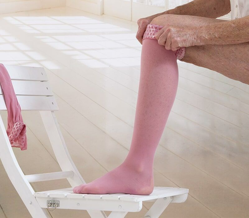 Person Putting on a Pink Compression Stocking — Ballina Home Healthcare Sales & Hire and Compression Stockings Plus in Ballina, NSW