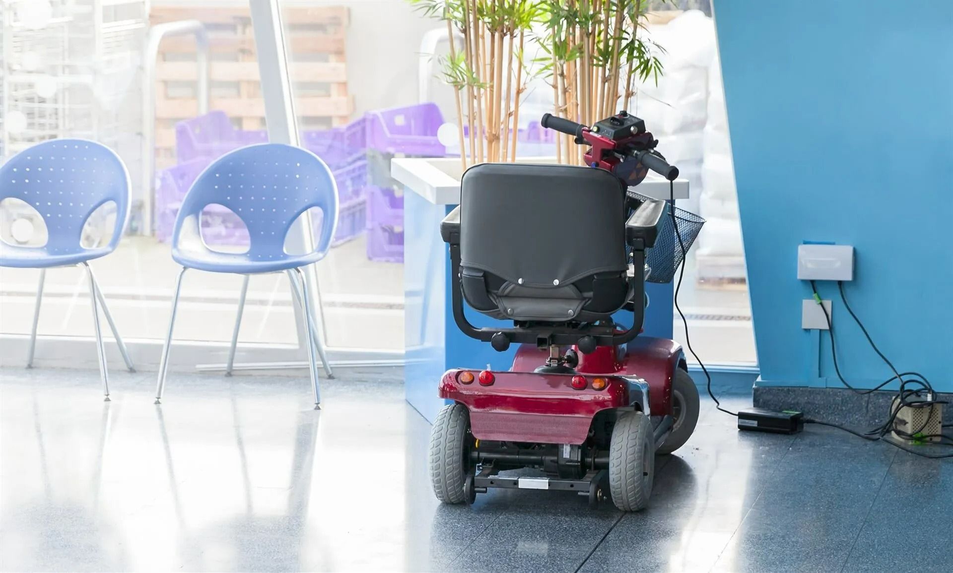 Red Mobility Scooter Charging Near Blue Wall and Chairs — Ballina Home Healthcare Sales & Hire and Compression Stockings Plus in Ballina, NSW