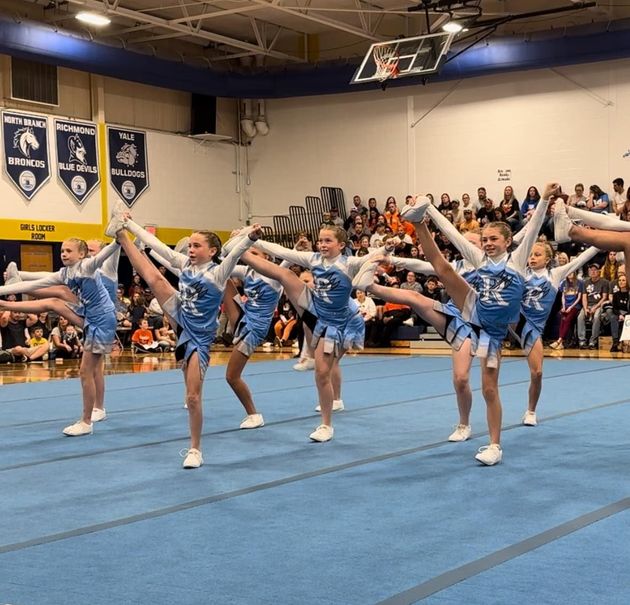 Red, white, and blue pom-poms held high by cheerleaders during a performance.