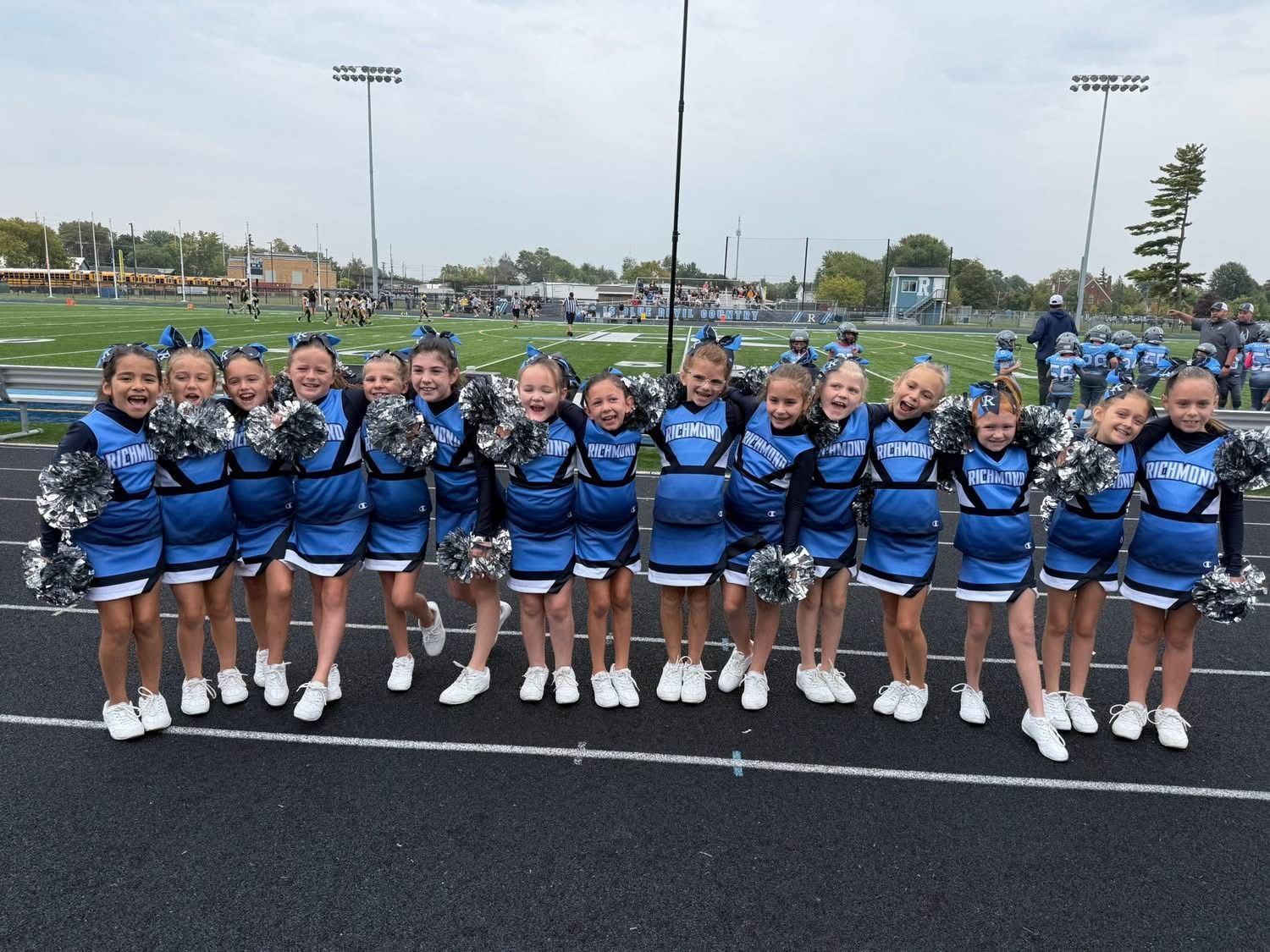 Cheerleader in red uniform performs a backbend on a green and red football field.
