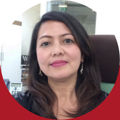 Woman with long brown hair, wearing earrings, sitting at a desk, with a red and white circular background.