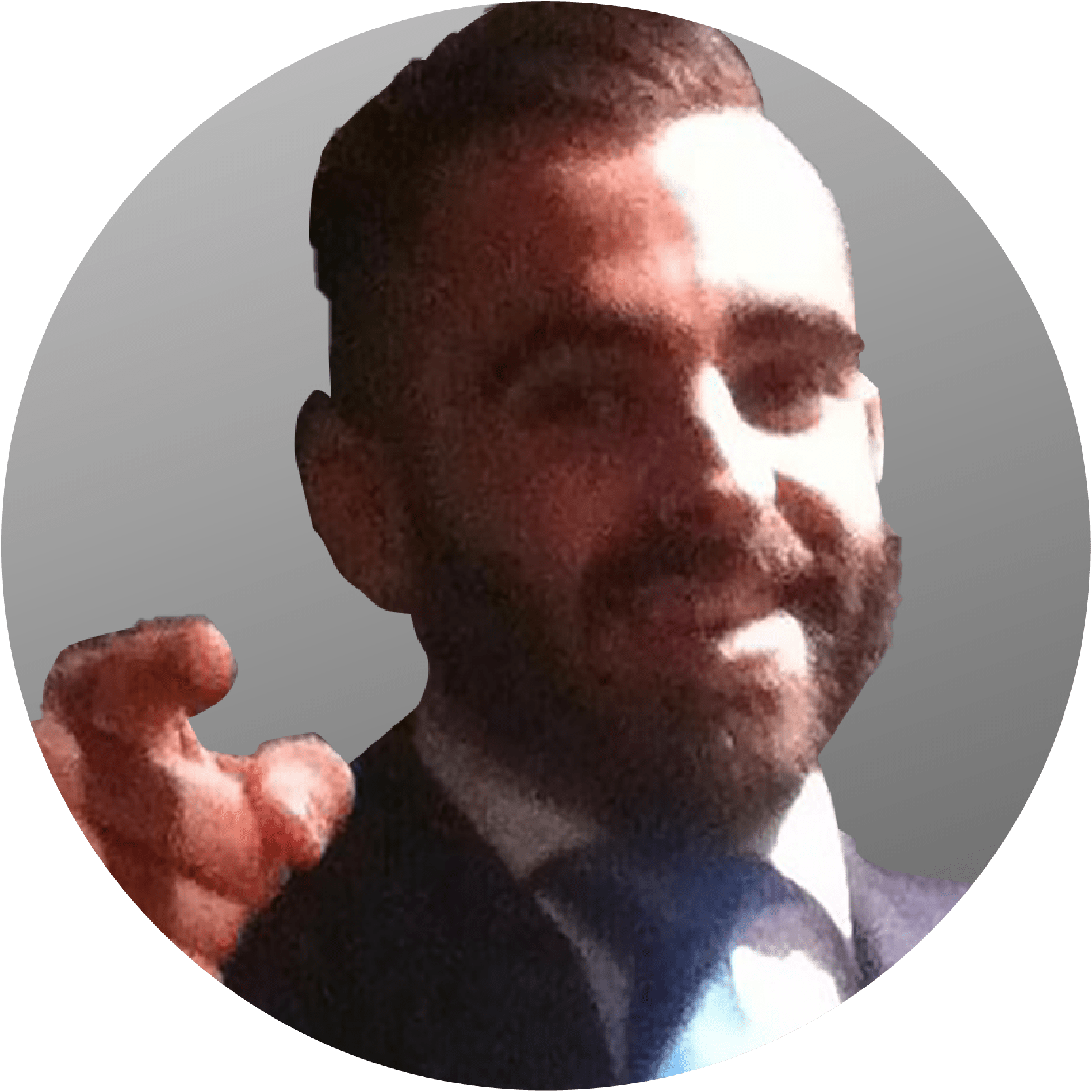 Man with a beard and suit gestures with his hand, smiling.