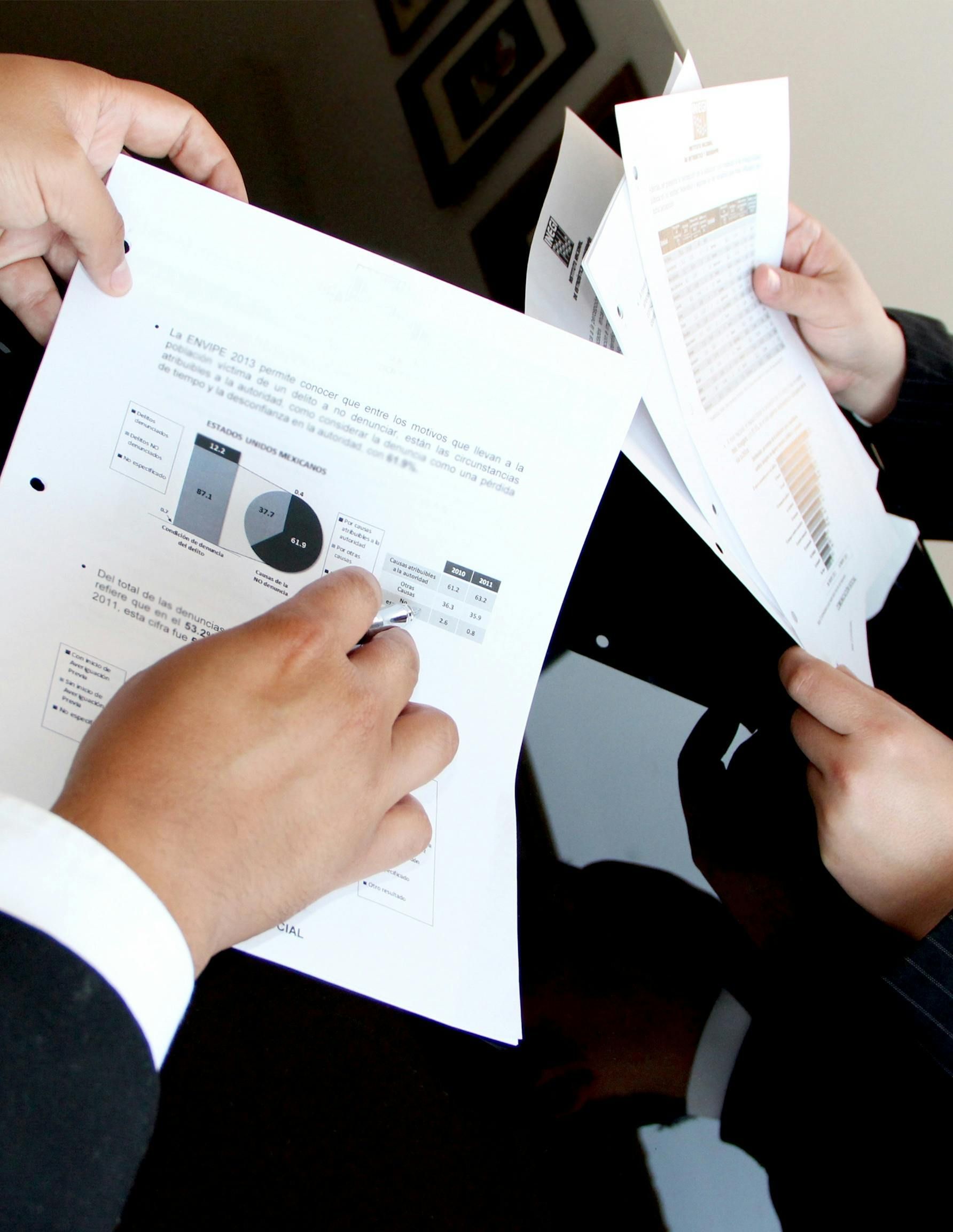 Two people reviewing documents with charts and data at a table.
