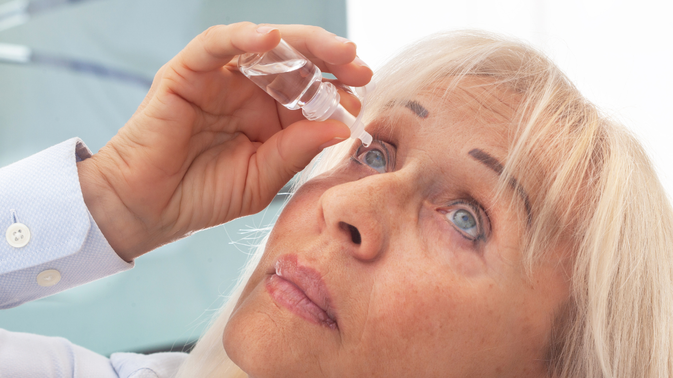 An elderly woman is wearing glasses and smiling.