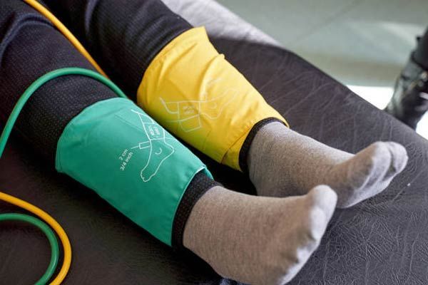 A person with a green and yellow sphygmomanometer on their leg