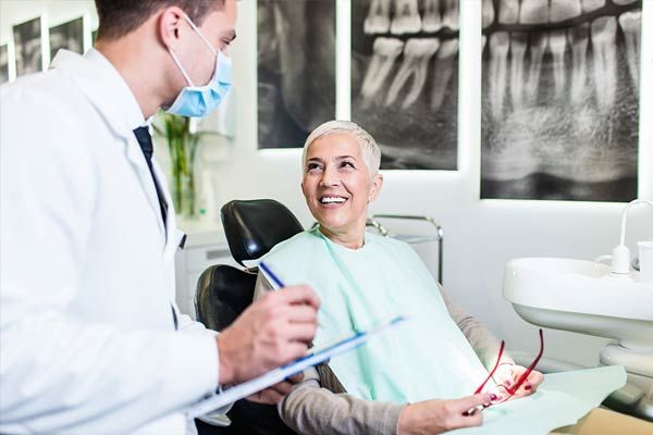 A dentist is talking to a patient in a dental chair.