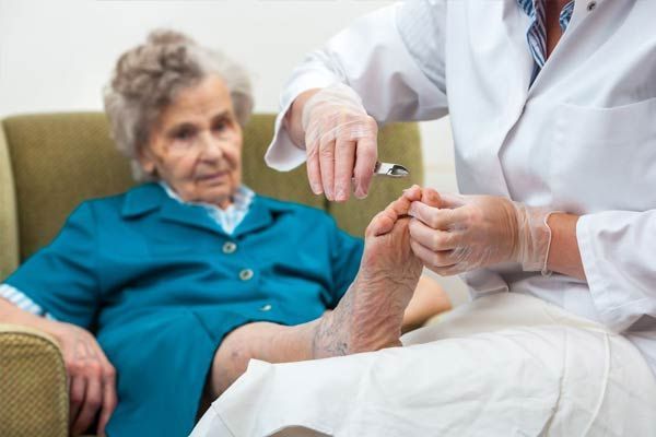 An elderly woman is getting her feet examined by a doctor.