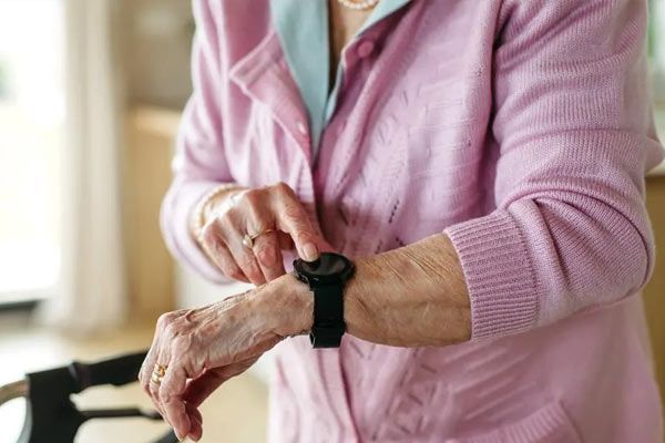 An elderly woman is wearing a smart watch on her wrist.