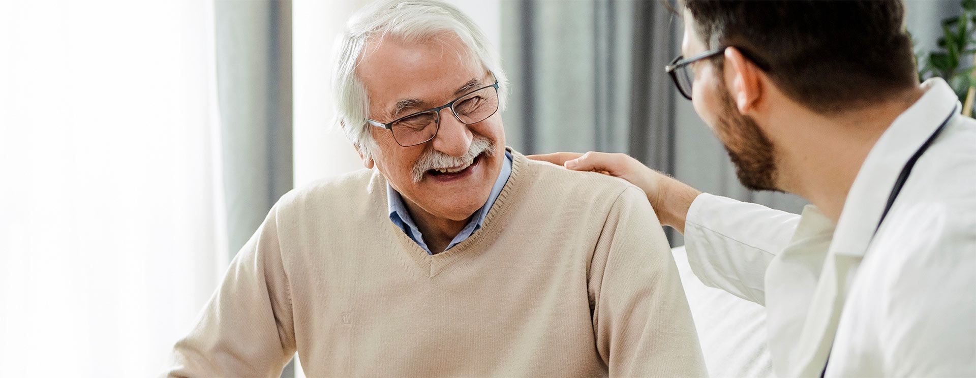 An elderly woman is wearing glasses and smiling.