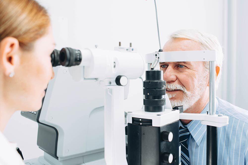 An older man is getting his eyes examined by an ophthalmologist.