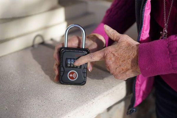 A person is holding a padlock in their hands and pointing at it.