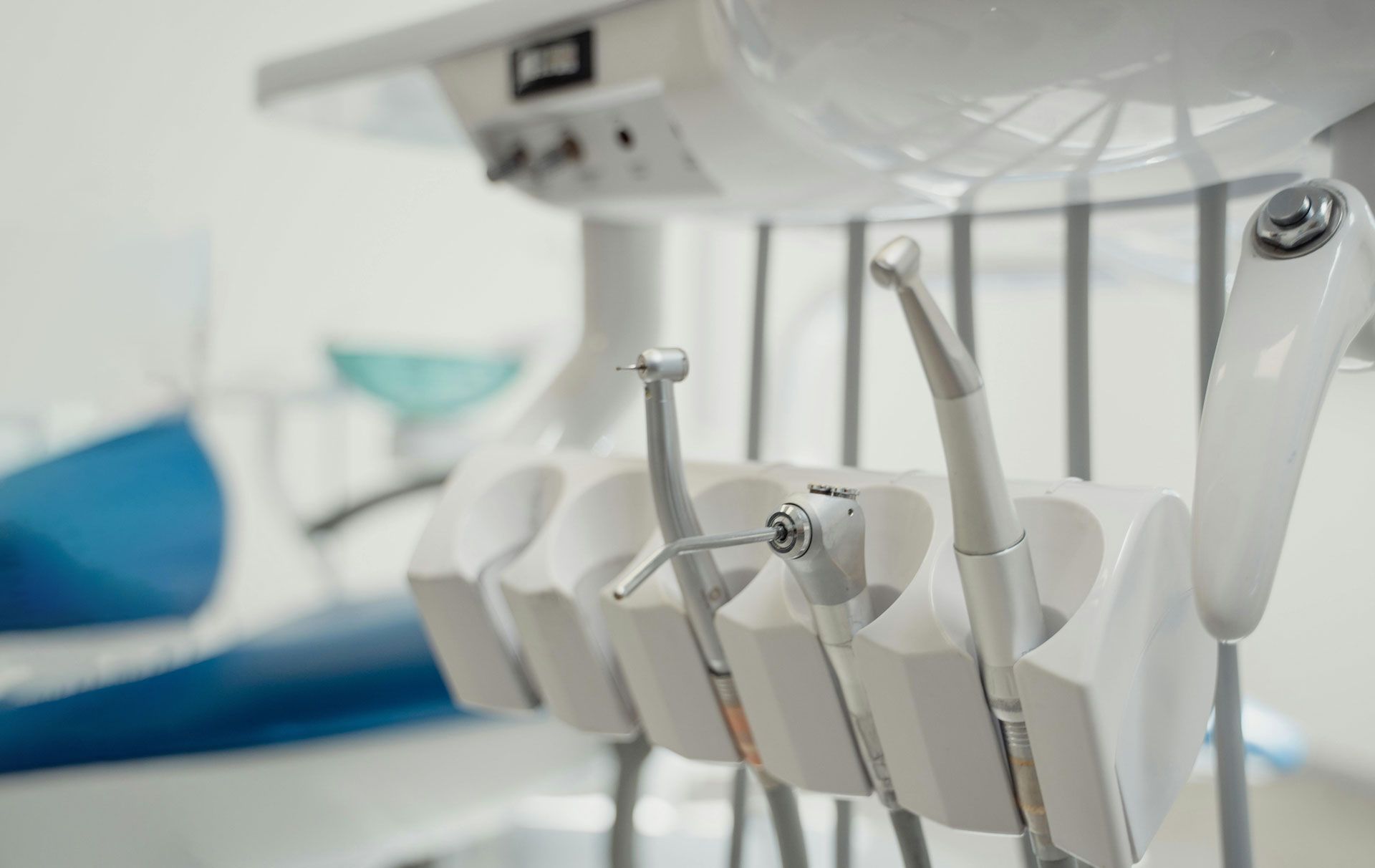 A close up of a dental chair with dental instruments hanging from it.