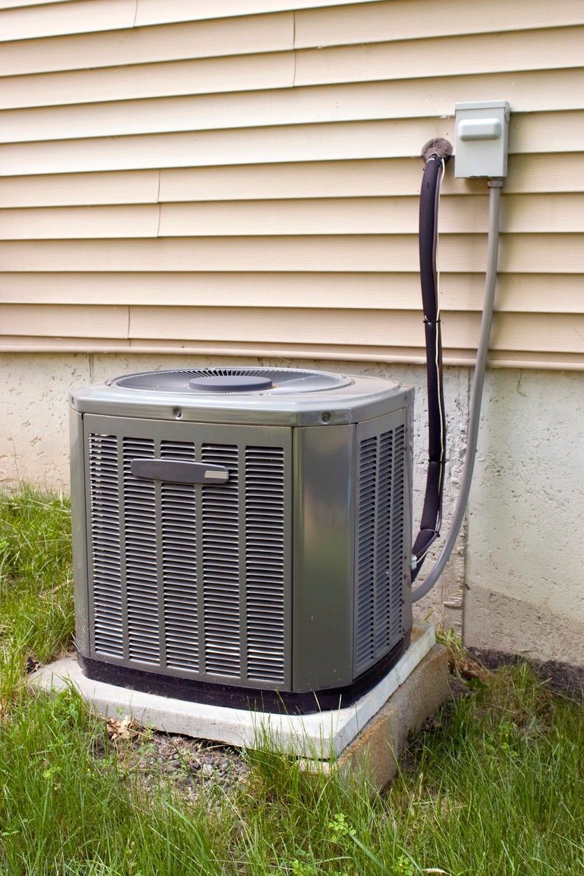 An air conditioner is attached to the side of a house.