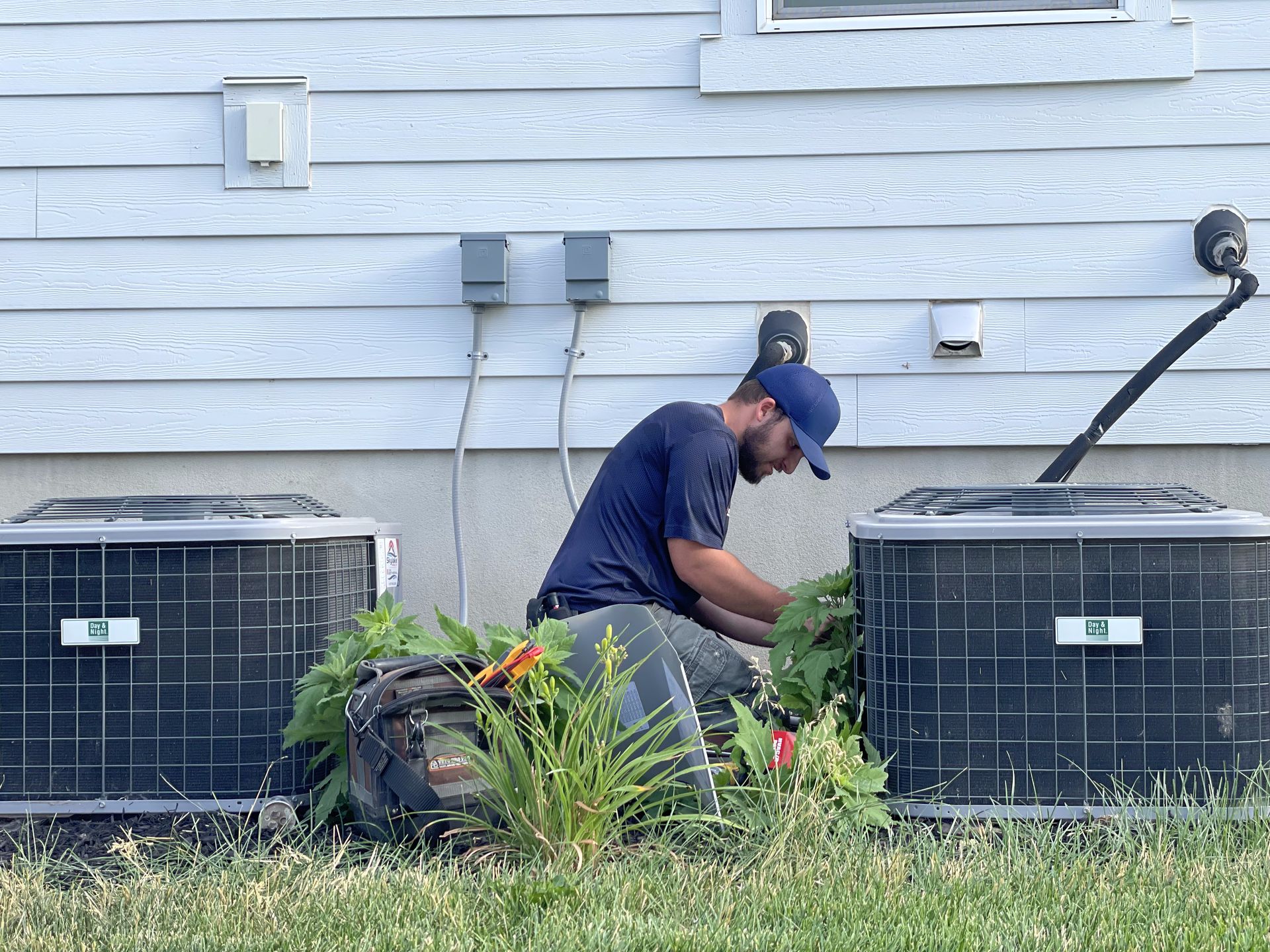 A man is working on an air conditioner outside of a house.