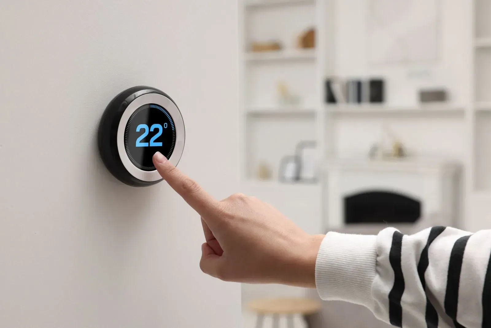 A person is pressing a button on a thermostat.