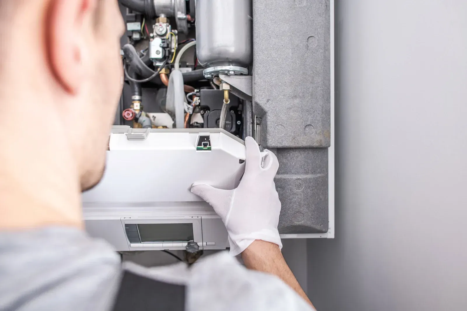A man is fixing a boiler in a house.