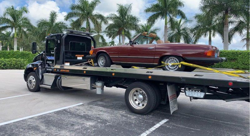 Black Truck Towing a Red Car | Naples Towing & Recovery