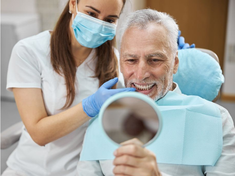 Dentist showing a patient his teeth with a mirror. Both are smiling.