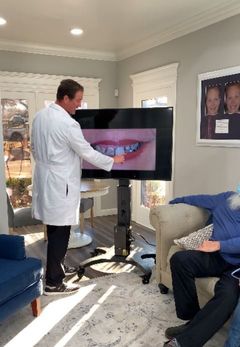 Dentist pointing at teeth on a screen during a consultation in an office.