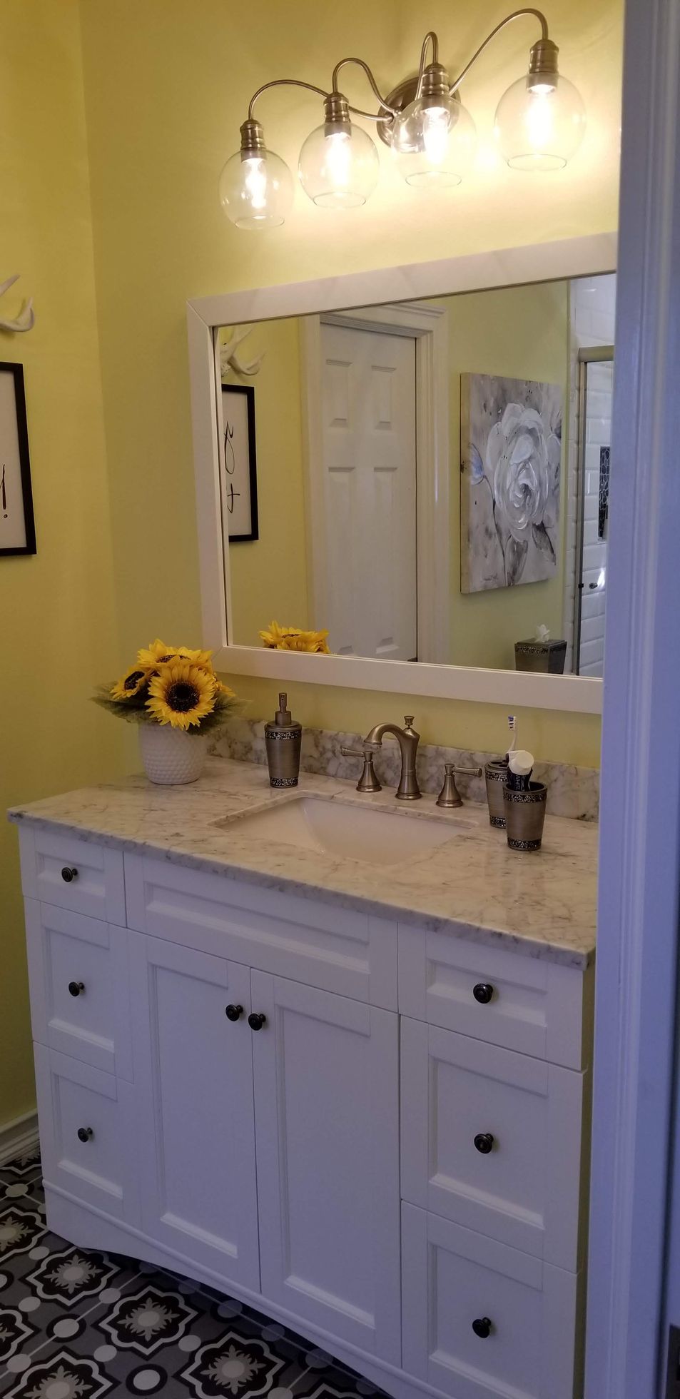 A bathroom with two sinks , a mirror , and sunflowers on the counter.