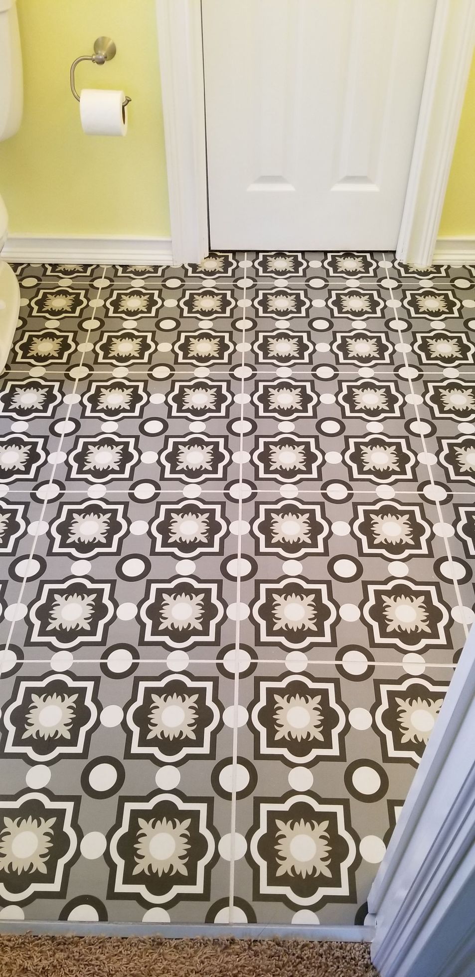 A bathroom with a black and white tile floor and a toilet.