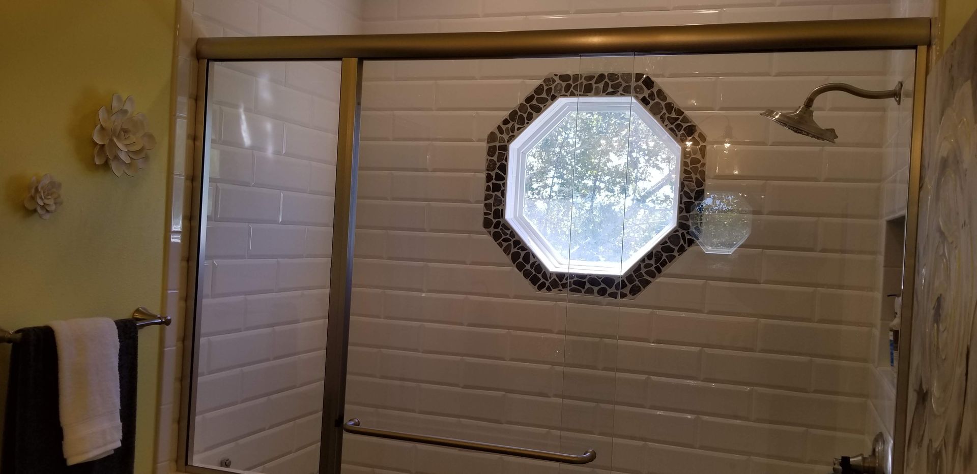 A bathroom with a sliding glass shower door and a window.