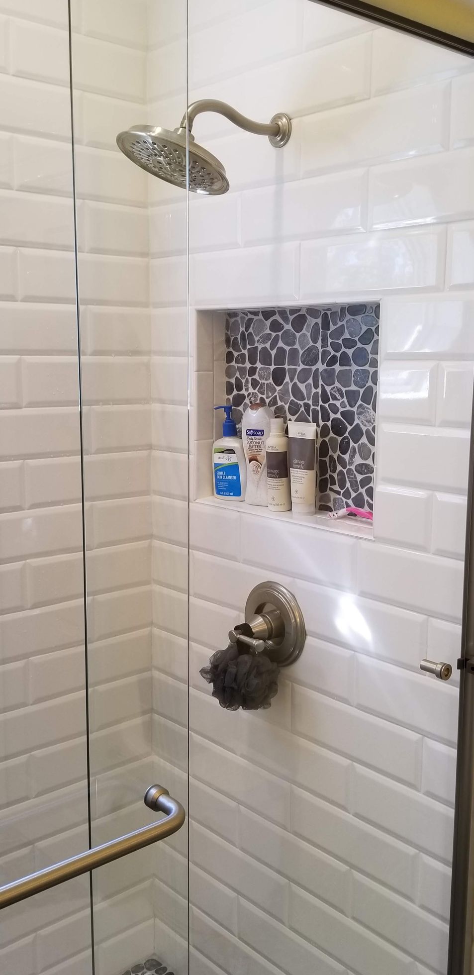 A shower with a glass door and a shower head.