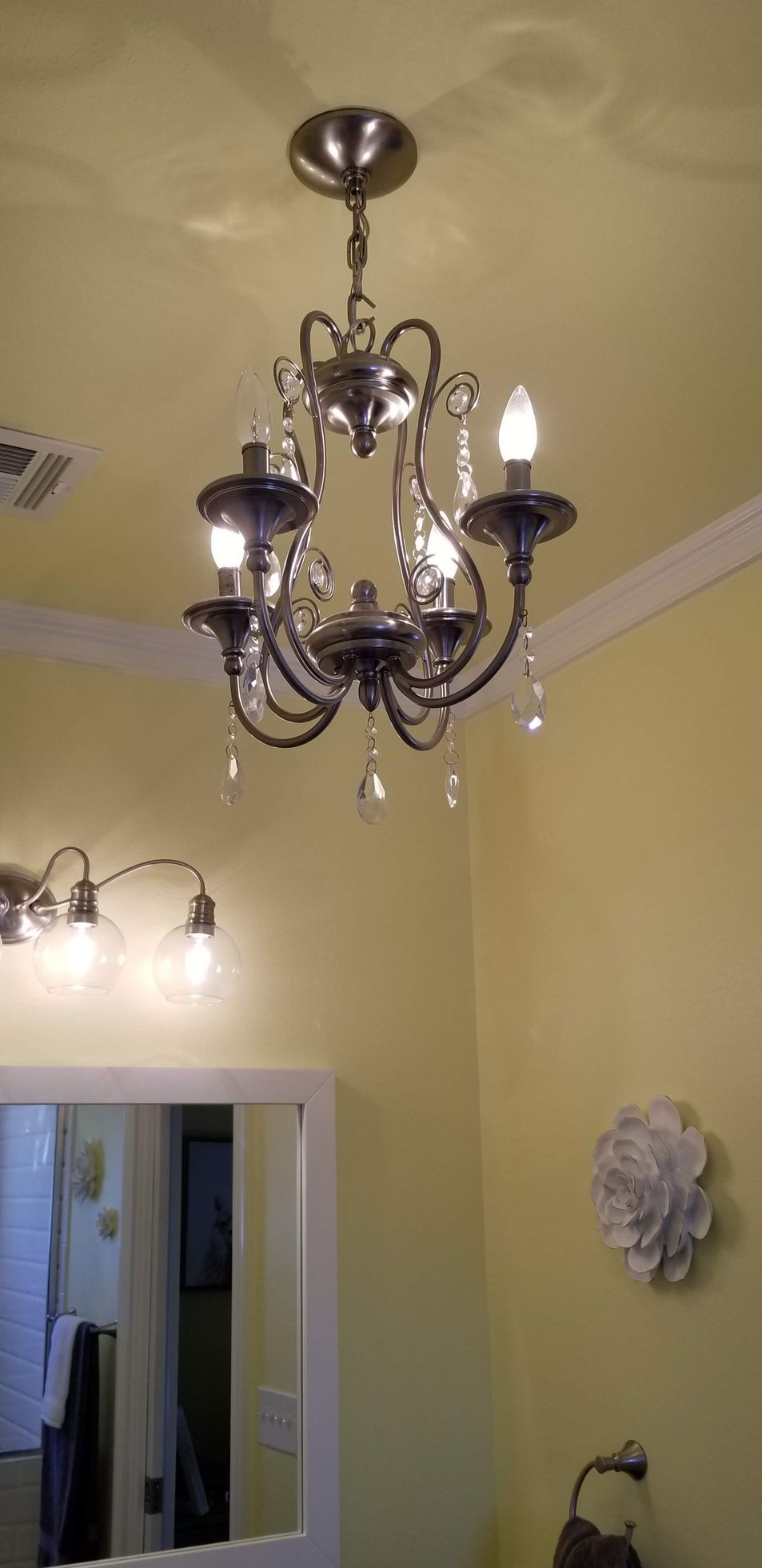 A chandelier is hanging from the ceiling in a bathroom.