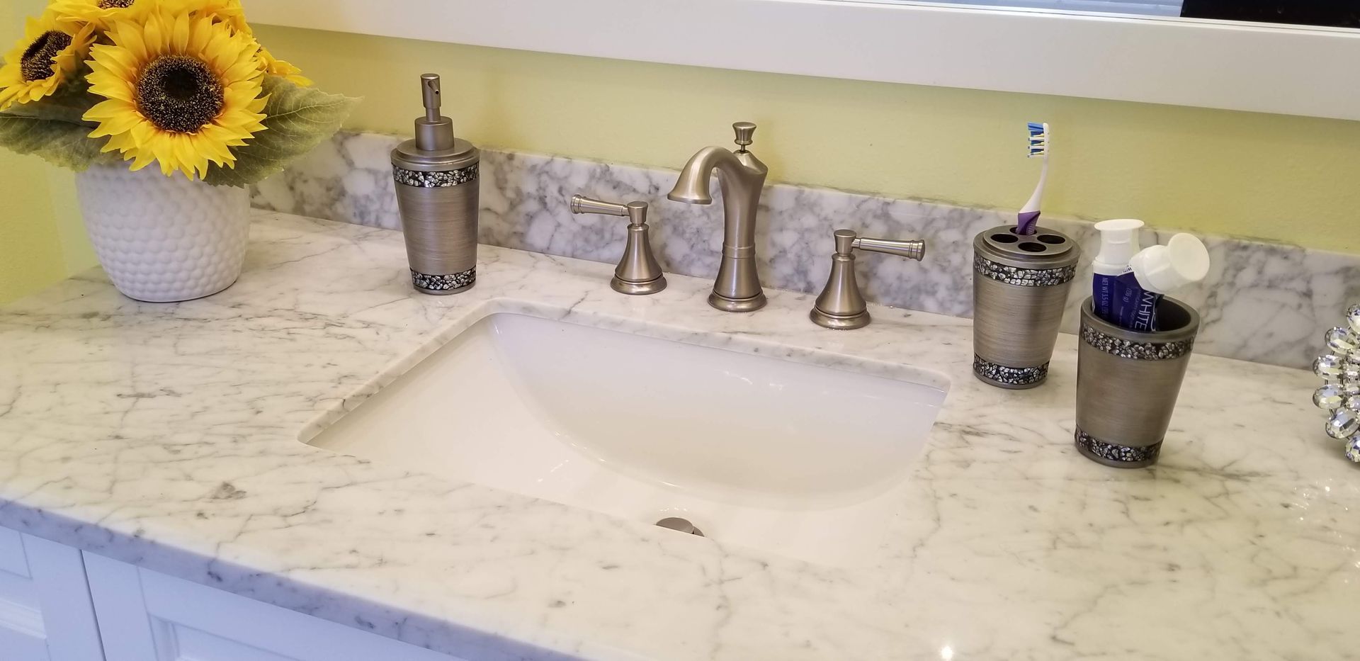A bathroom sink with a vase of sunflowers on the counter.