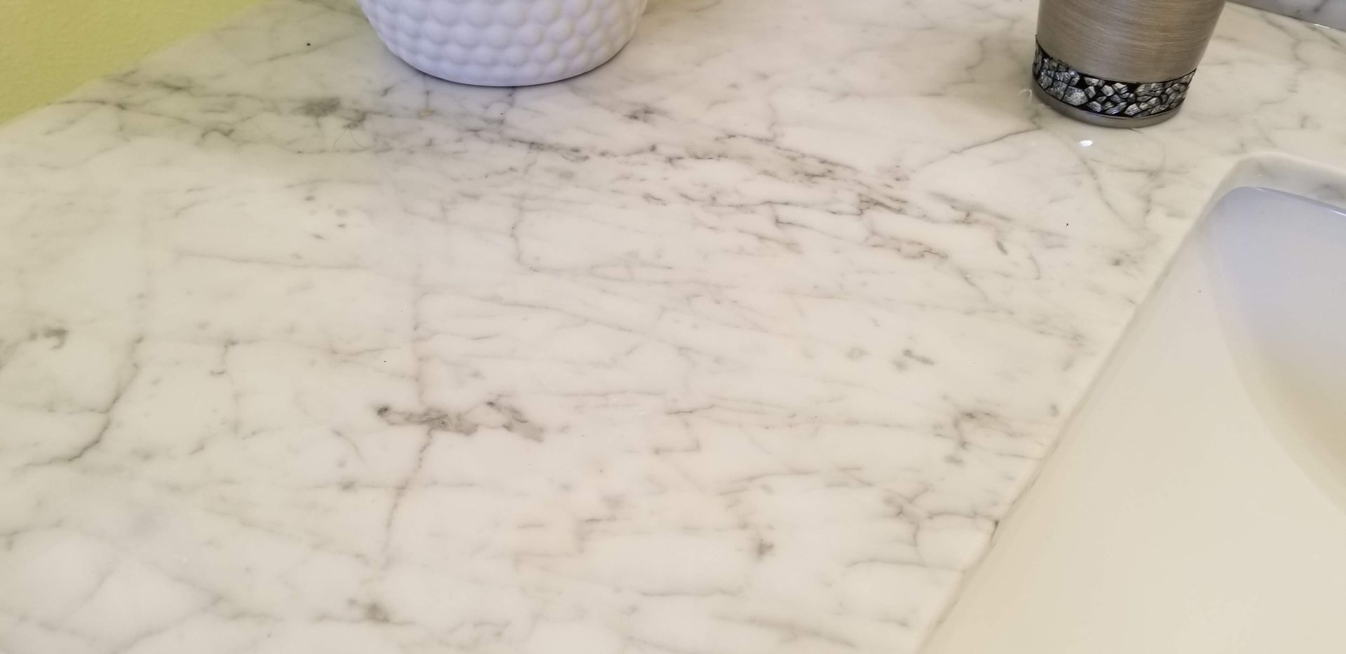 A white marble counter top next to a sink in a bathroom.