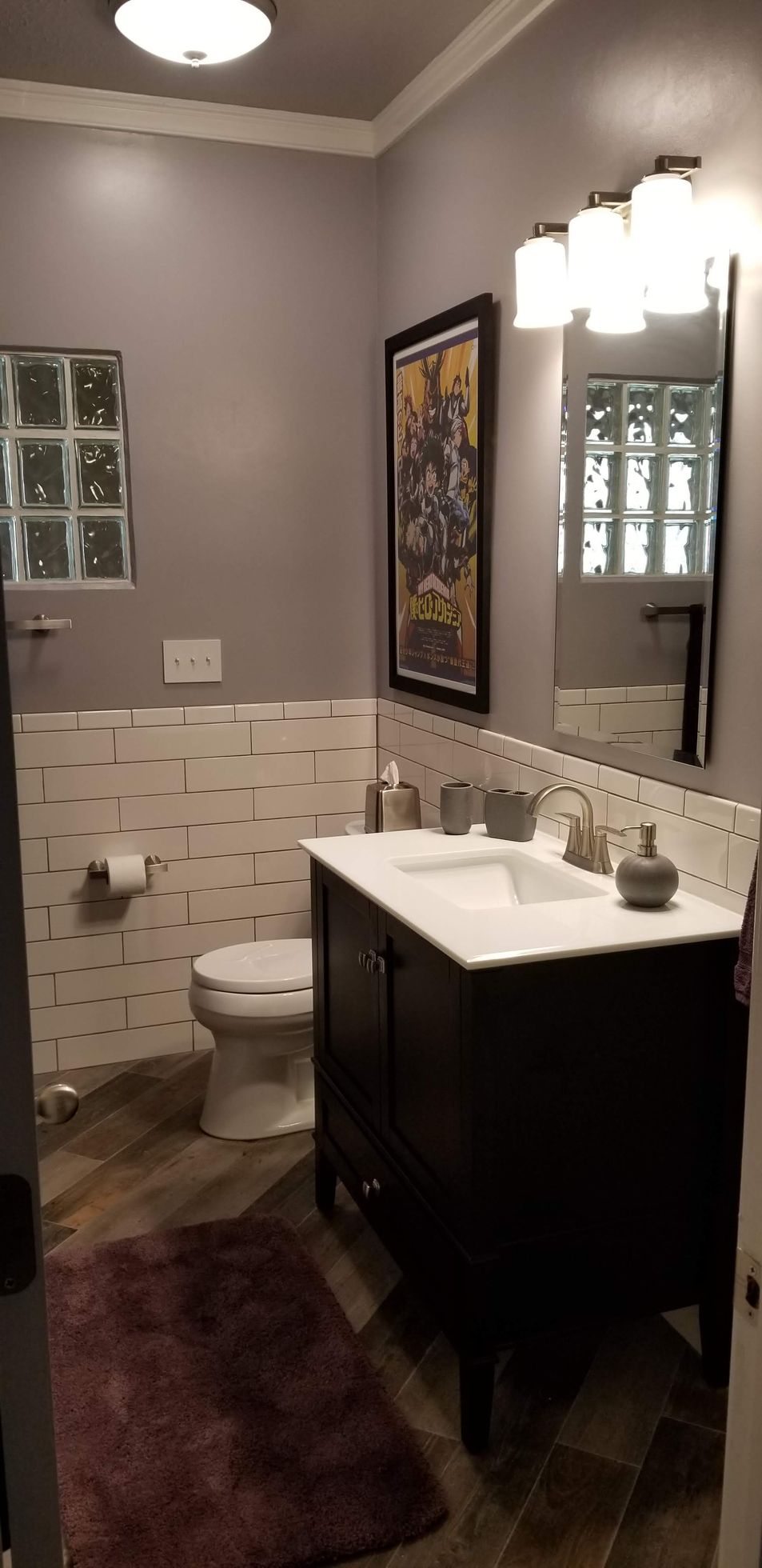 A bathroom with a toilet , sink and mirror.