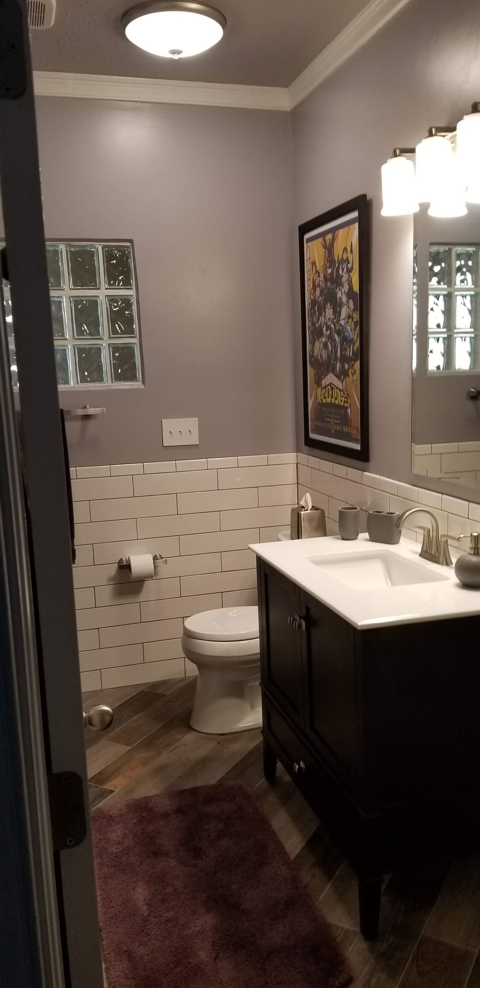 A bathroom with a toilet , sink and mirror.