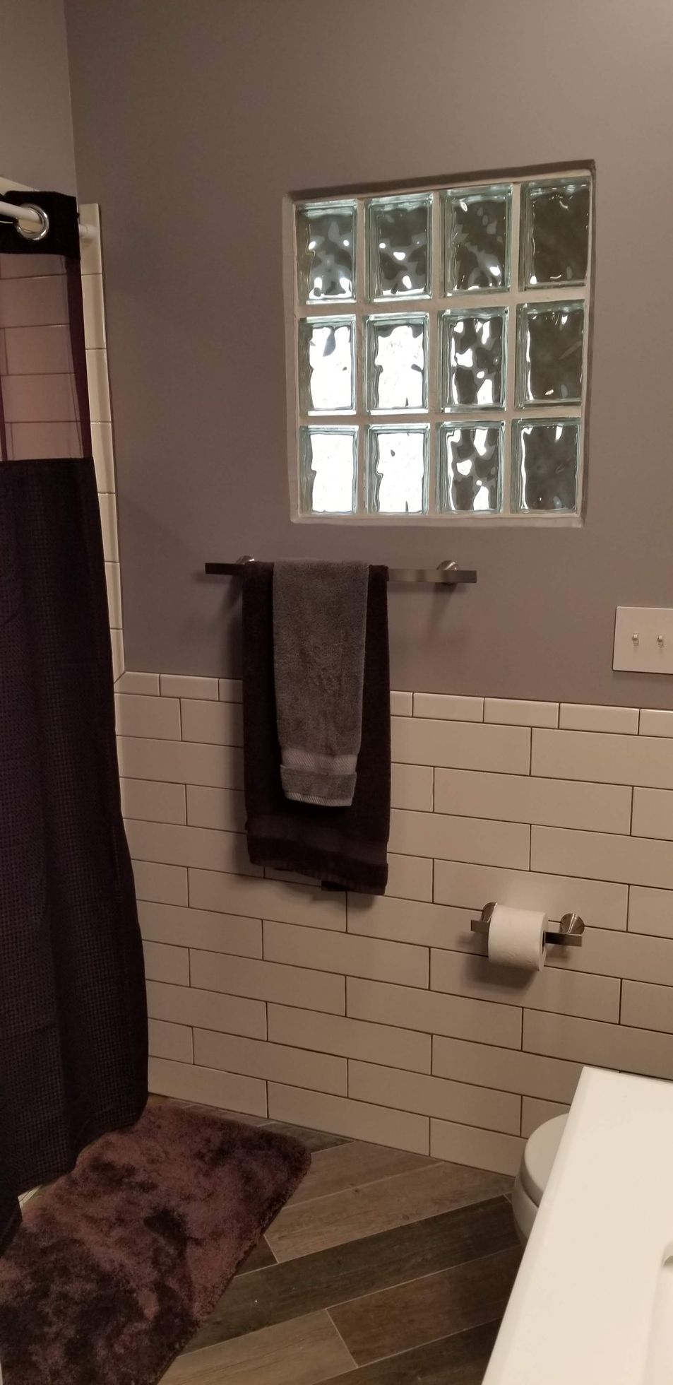 A bathroom with a glass block window and a towel rack.