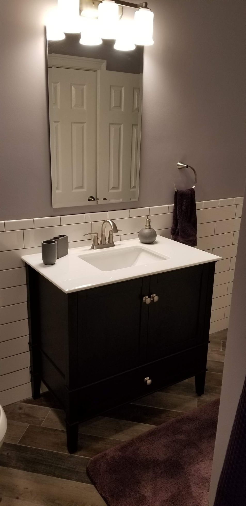 A bathroom with a sink , mirror and towel rack.