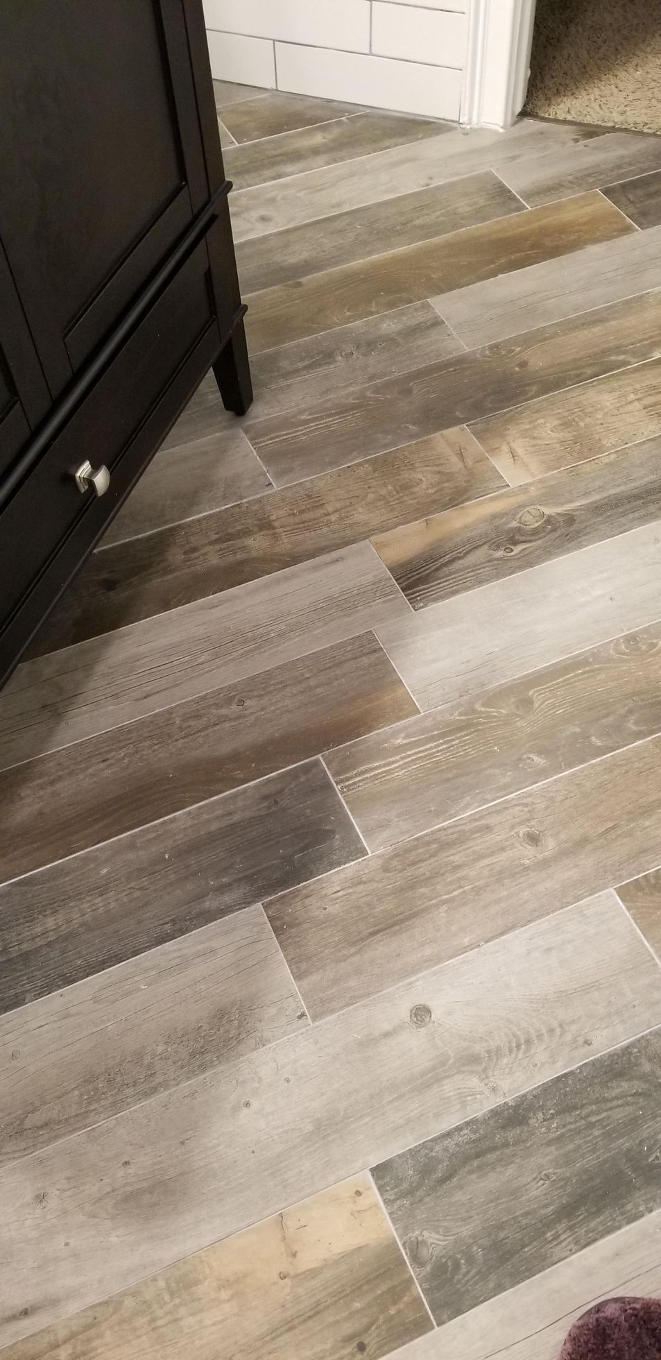 A close up of a wooden floor with a cabinet in the background.