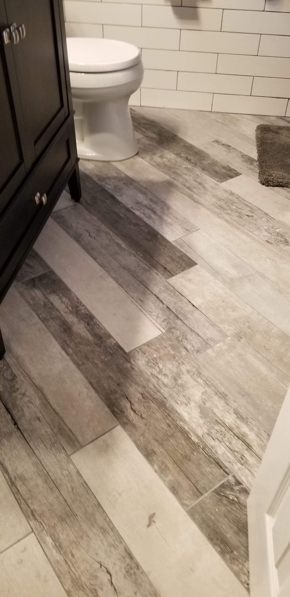 A bathroom with a toilet , sink , and wooden floor.