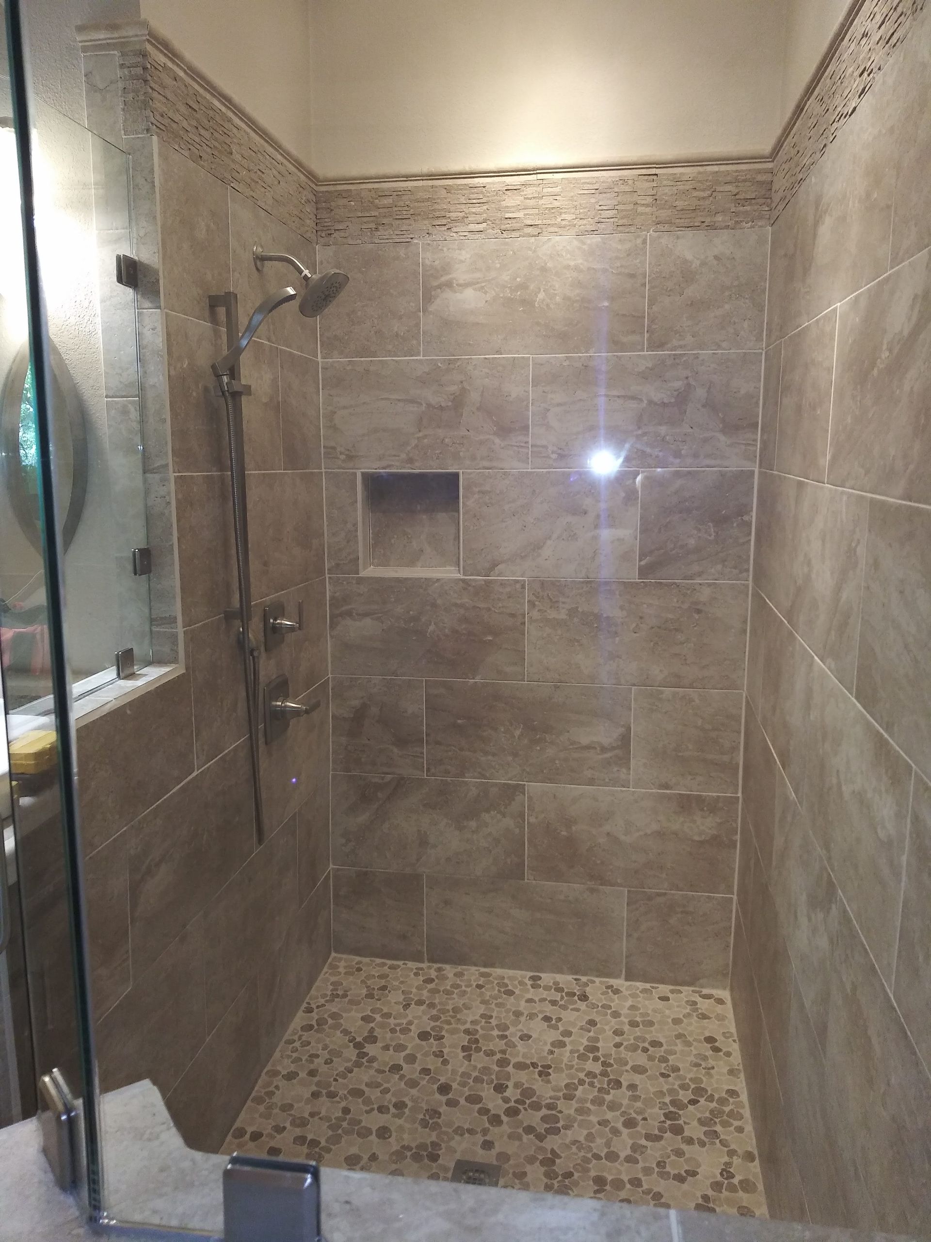 A bathroom with a walk in shower with a glass door