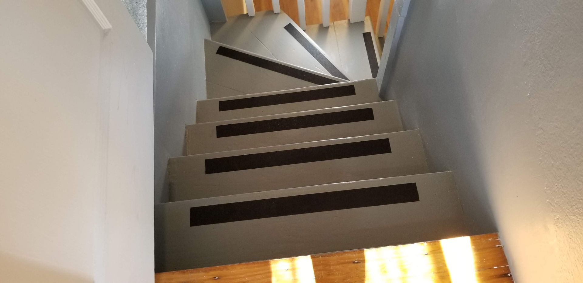 A staircase with black stripes on the steps and a wooden railing.