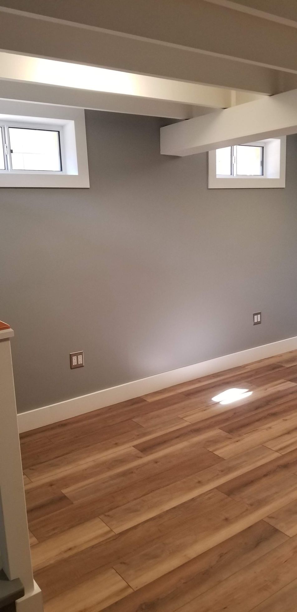 An empty room with a wooden floor and gray walls.