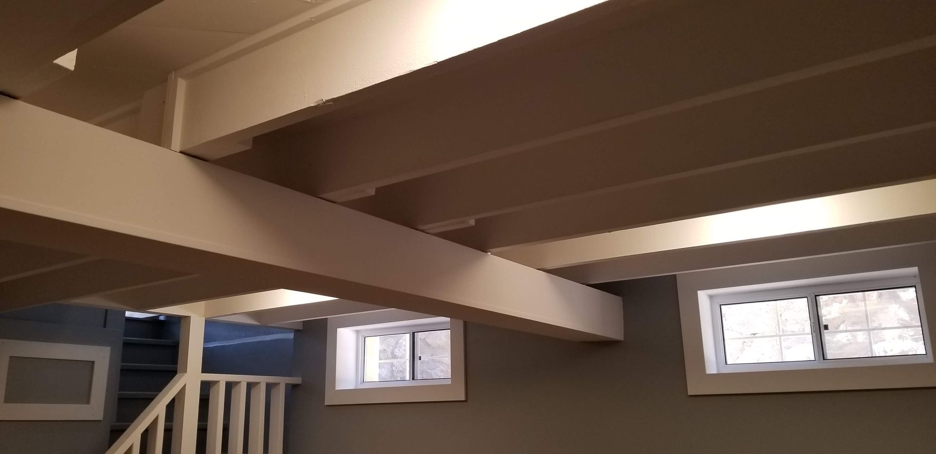 A room with a staircase and a ceiling with white beams