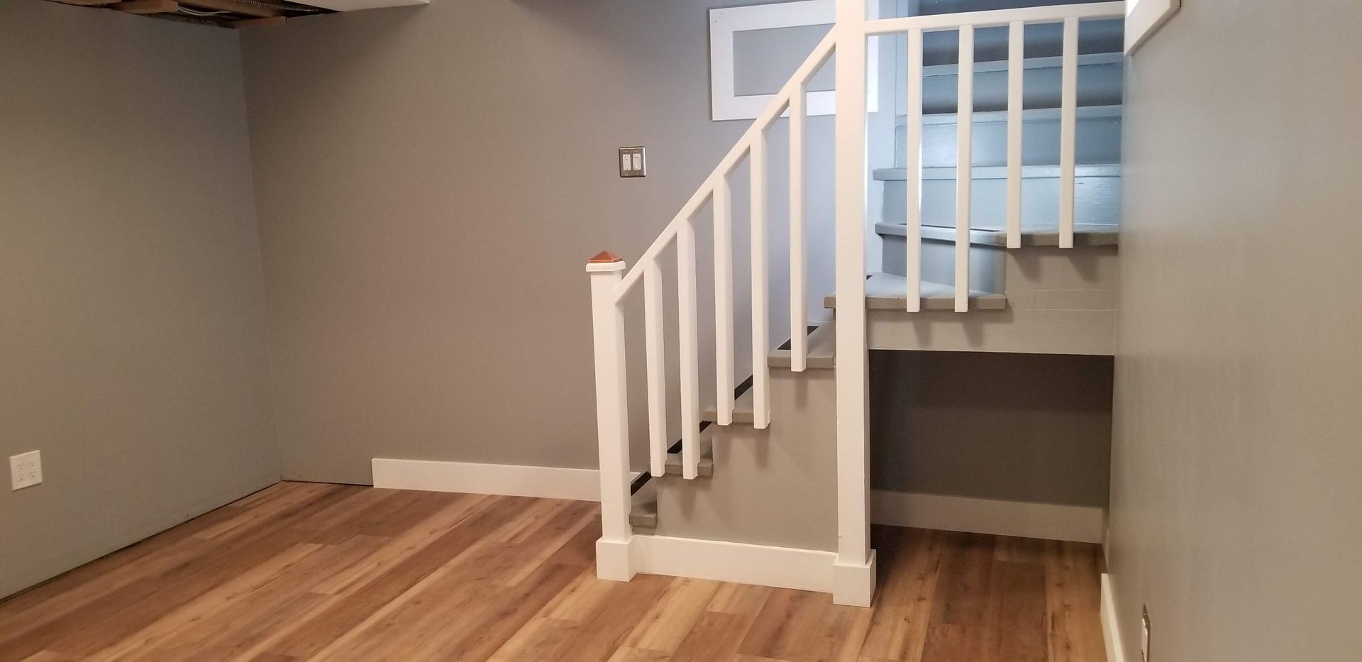An empty room with hardwood floors and stairs leading up to the second floor.