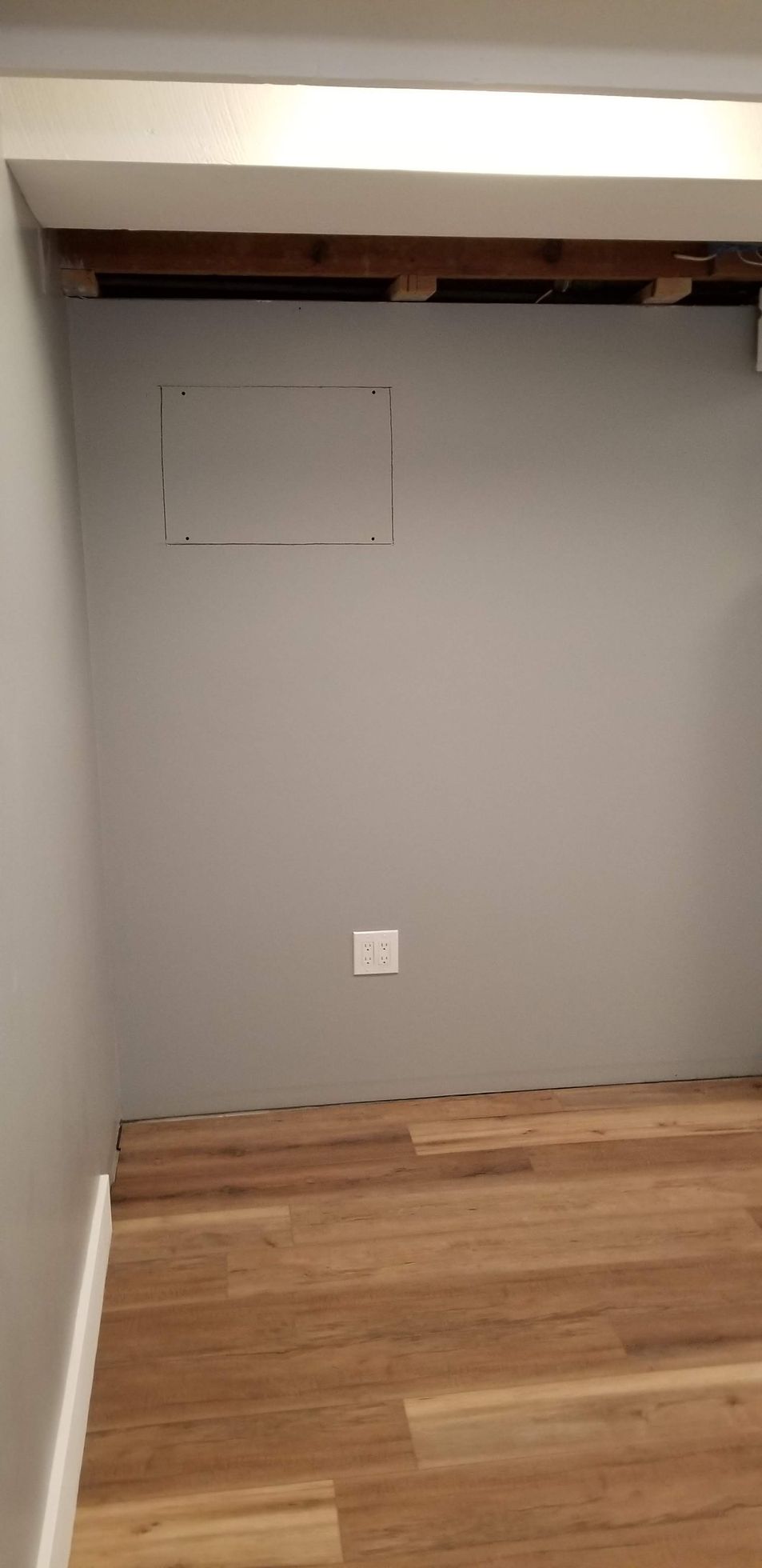 An empty room with a wooden floor and a gray wall.