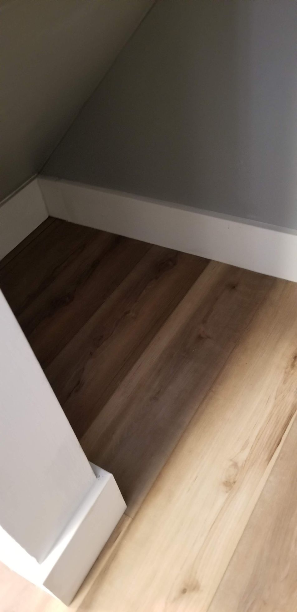 A corner of a room with a wooden floor and white trim.