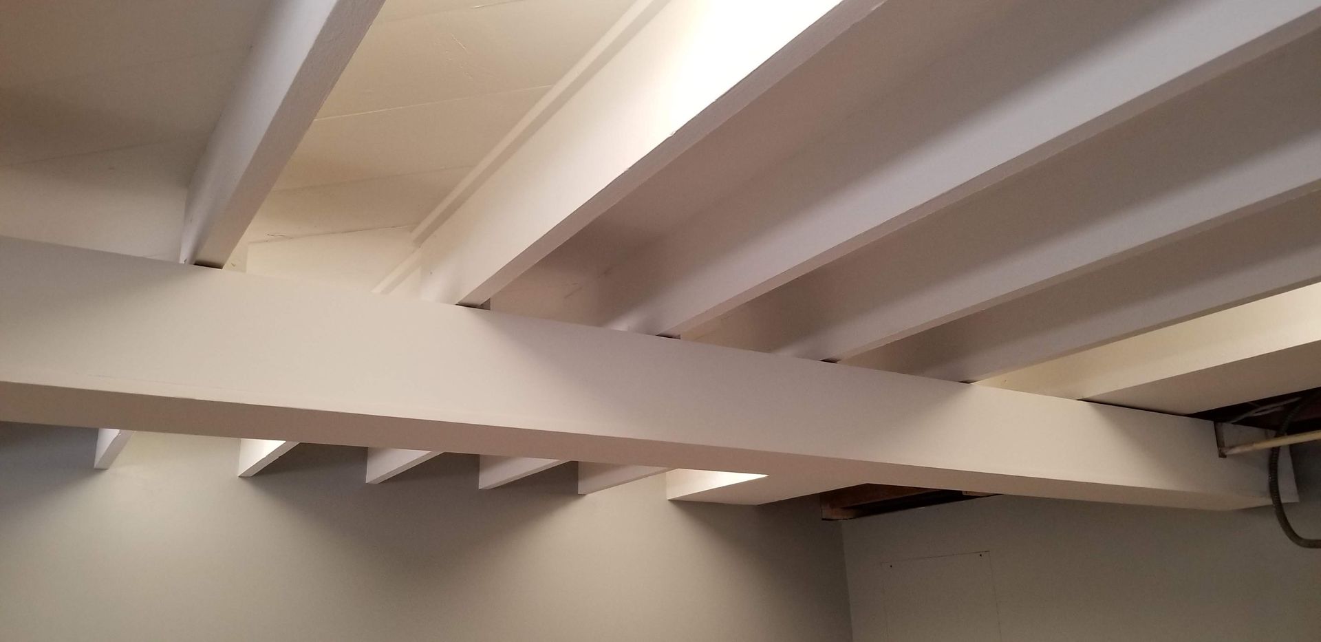 A ceiling with white beams and a white wall